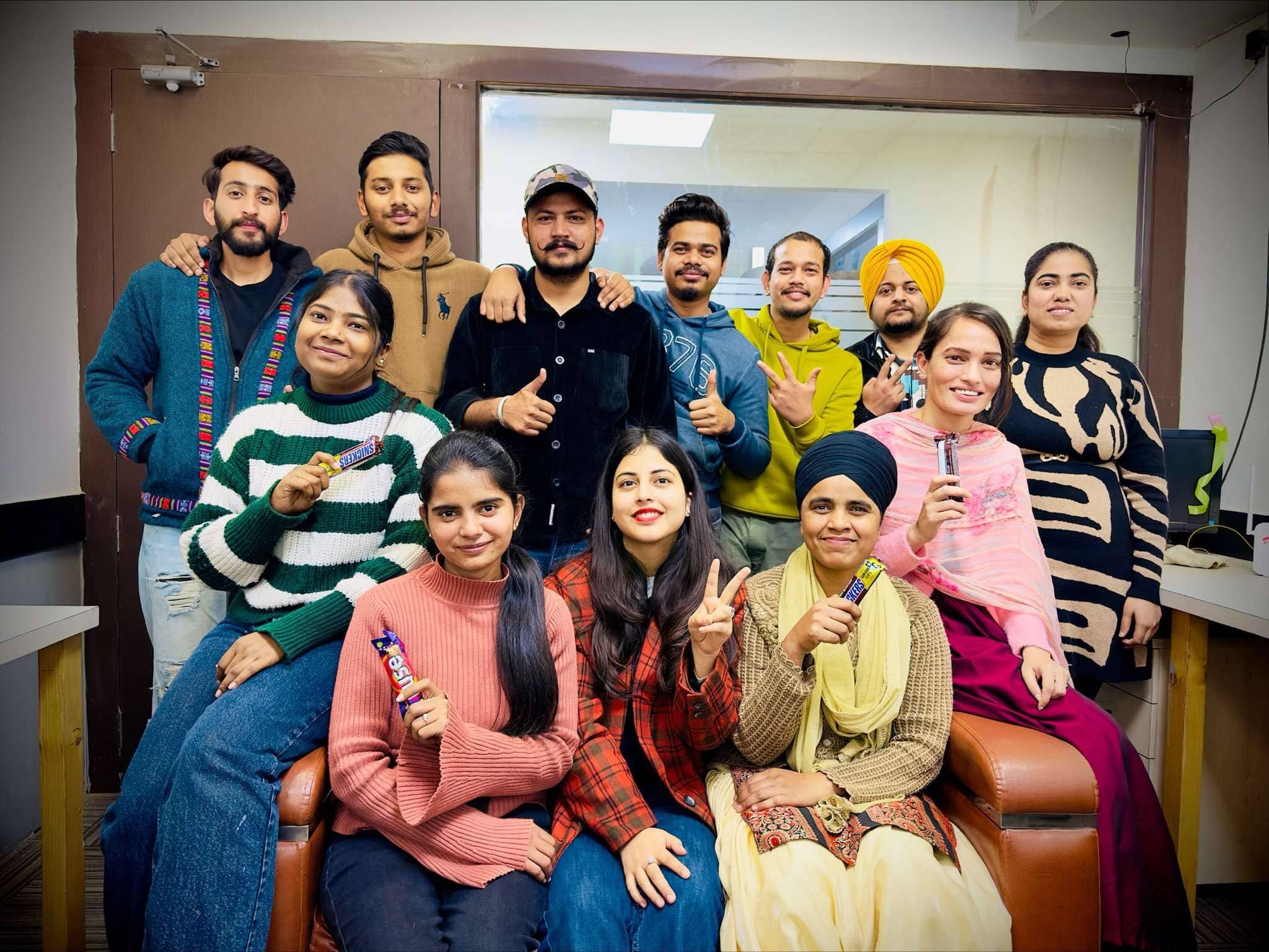 Whizcamp team celebrating in the office with smiles and chocolate bars