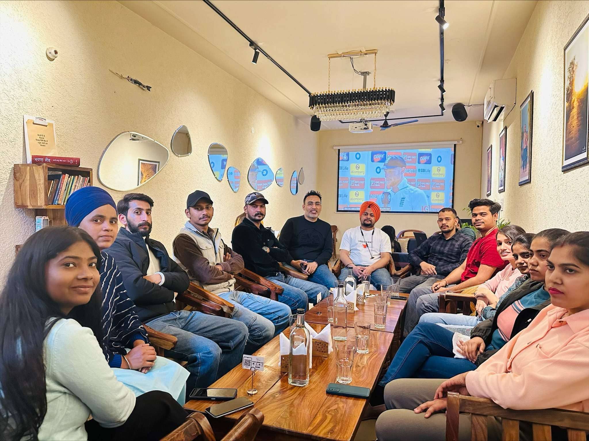 Whizcamp team in a meeting room discussing ideas with a screen presentation in the background